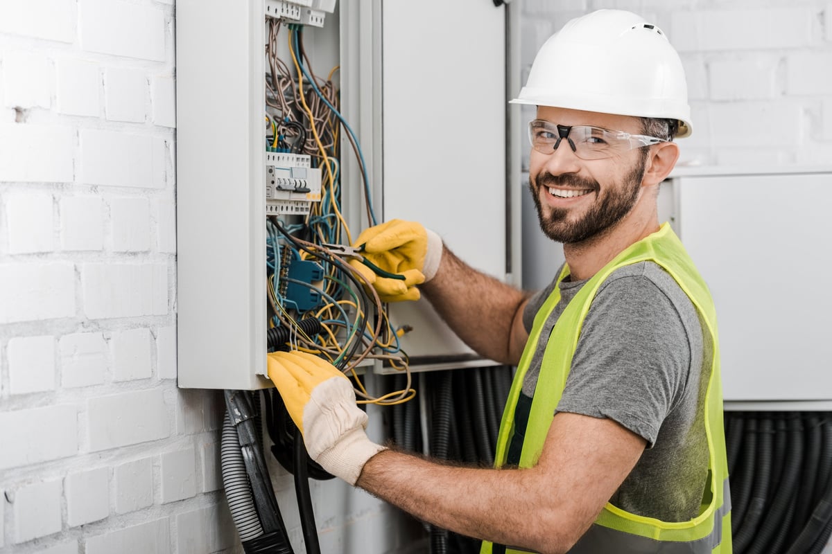 Electrician holding pliers while repairing an electrical box