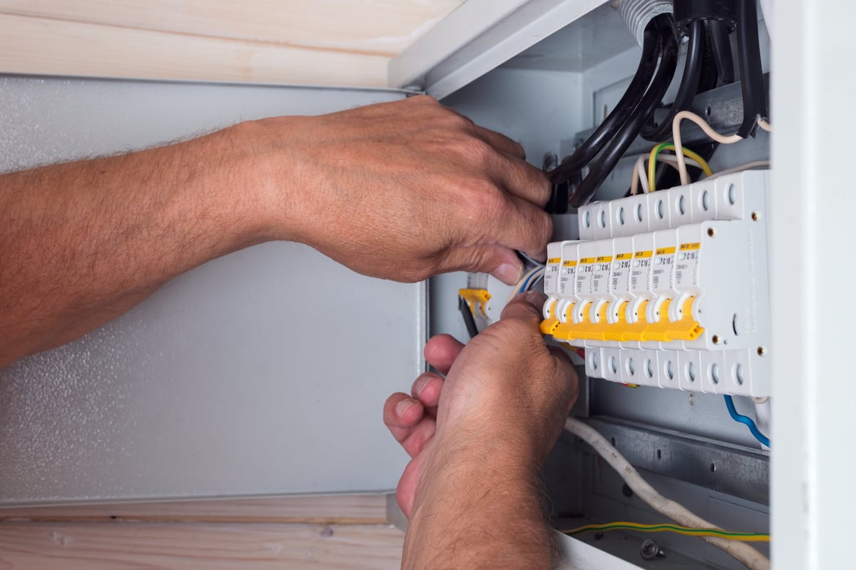 Electrician connecting cables inside an open distribution board