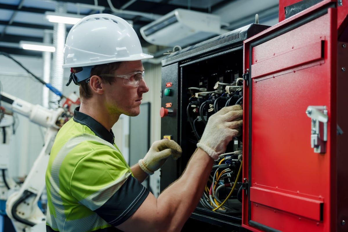 Engineer inspecting an industrial control cabinet during a maintenance check