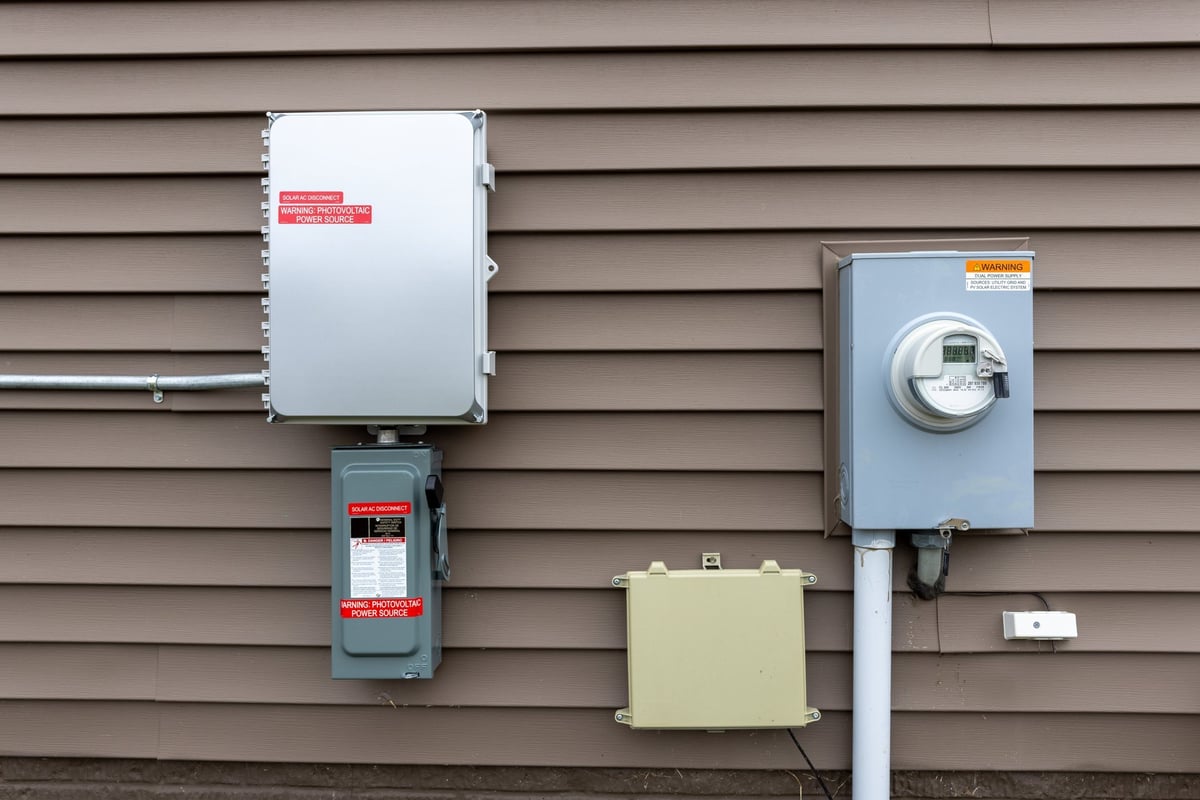 Solar power inverter and breaker mounted next to an electric meter on a home exterior
