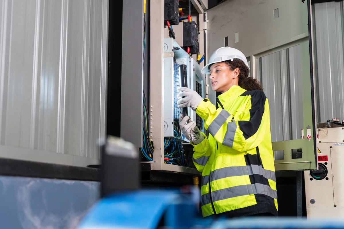 Technician with a flashlight inspecting an electrical panel in a facility